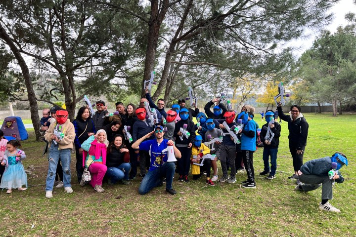 a group of people standing on top of a grass covered field